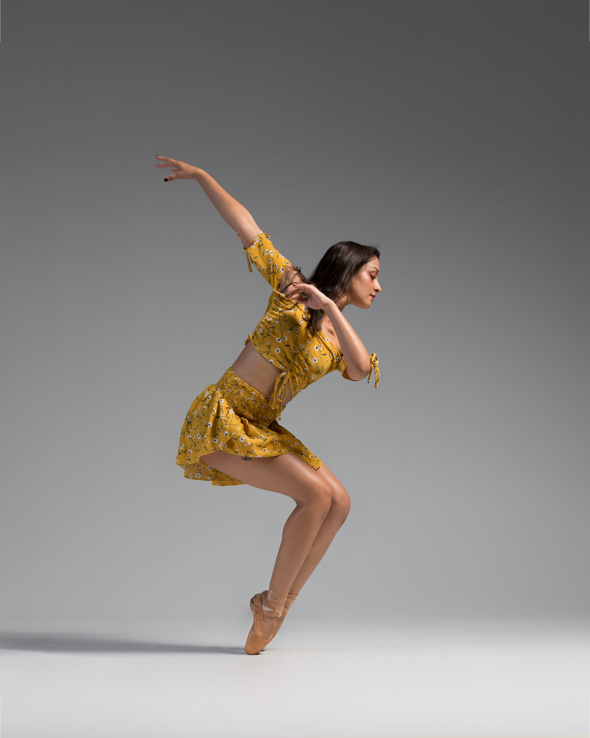 A woman in yellow is dancing on the floor