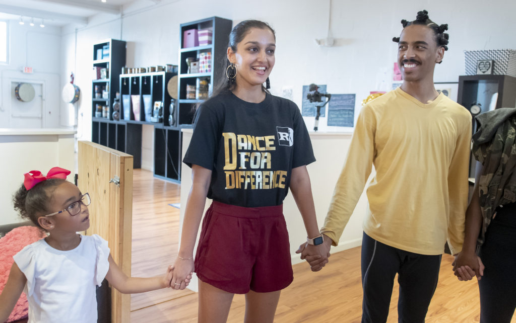 A couple of people holding hands while standing in a room.