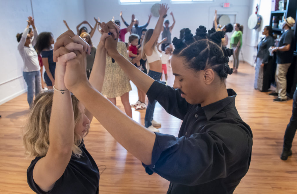 A man and woman holding hands in the middle of an exercise class.