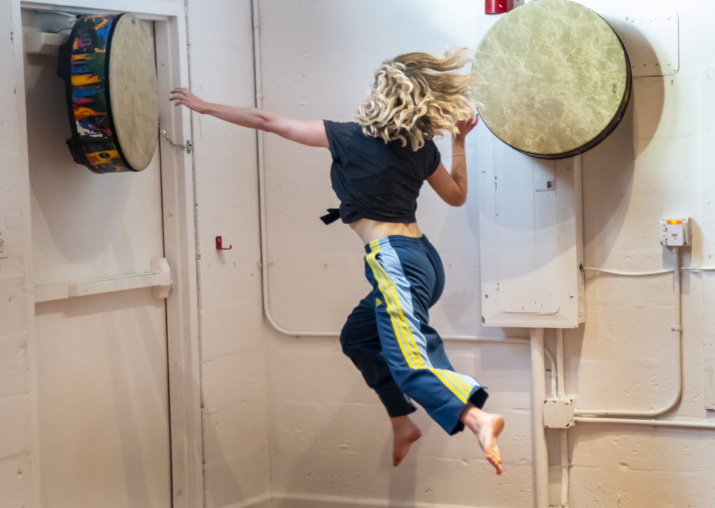 A woman jumping in the air with her arms outstretched.