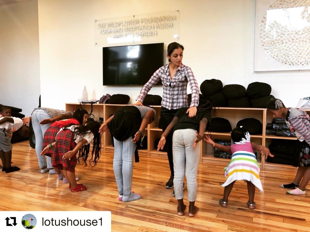 A woman standing on the floor teaching dance to some kids