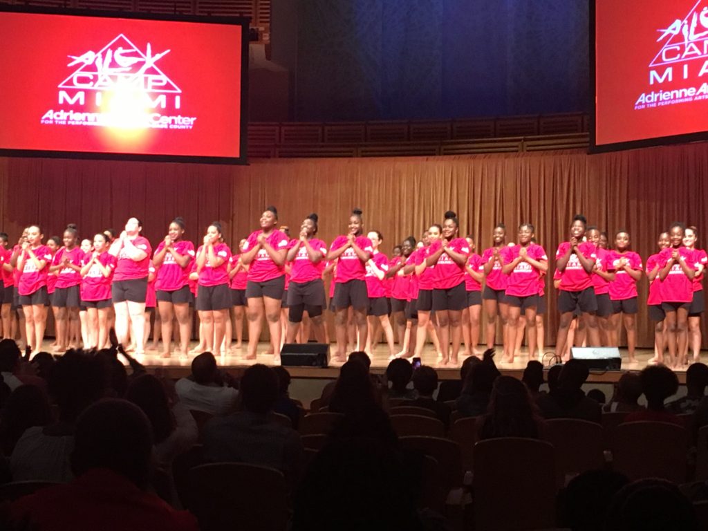 A group of women in red Ailey Camp shirts on stage.