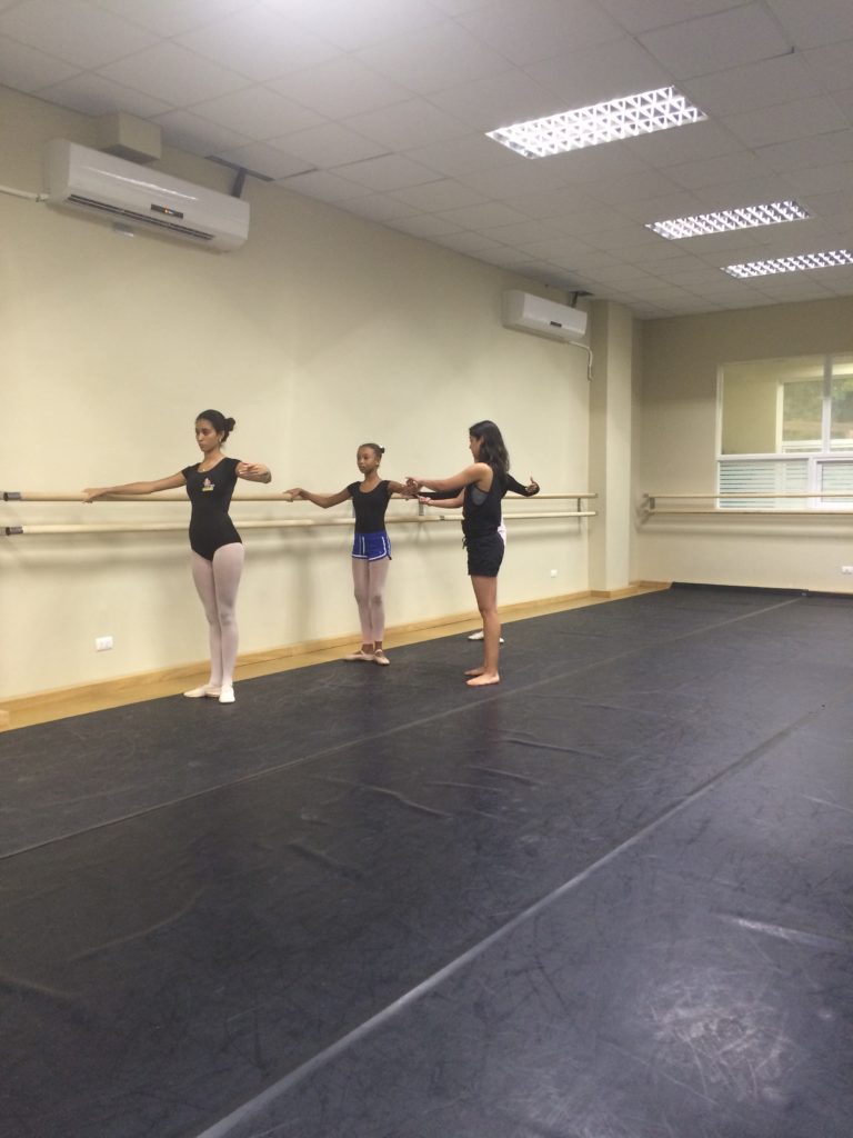 Three young girls are practicing ballet in a studio.
