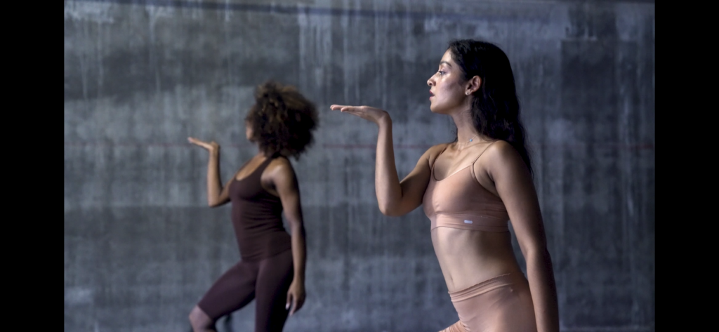 Two women in tan outfits are performing a dance.