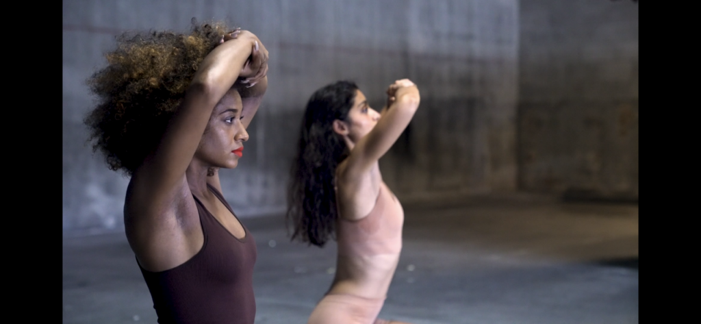 Two women are performing a dance in the middle of a garage.