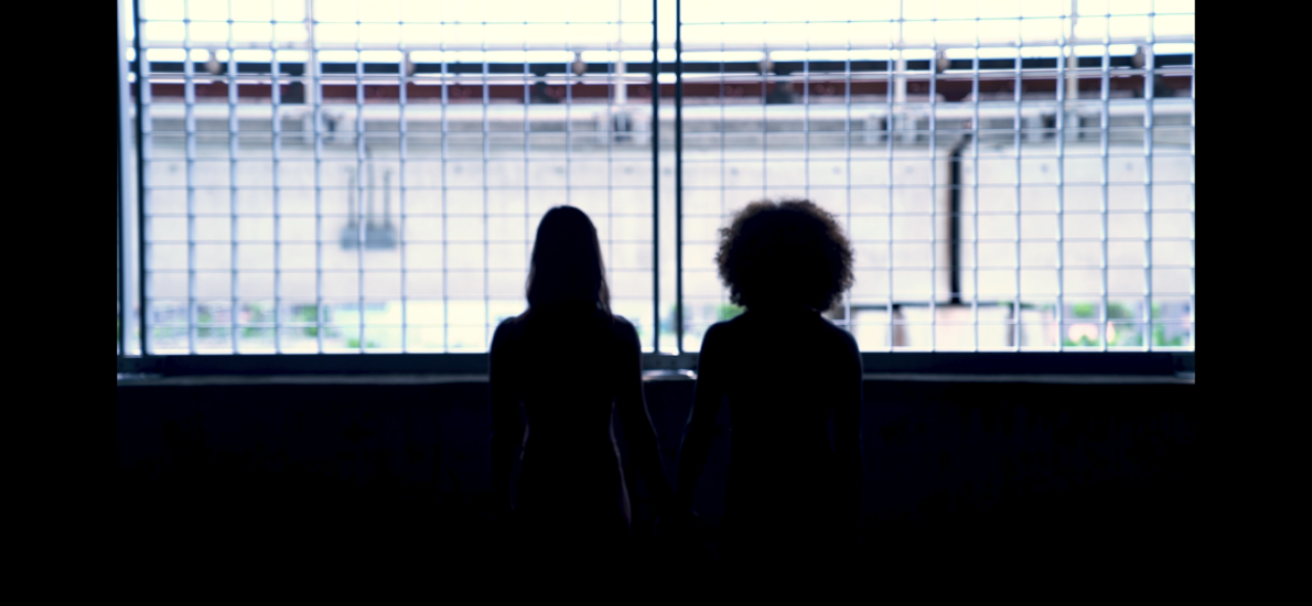 Two women are standing in front of a window.