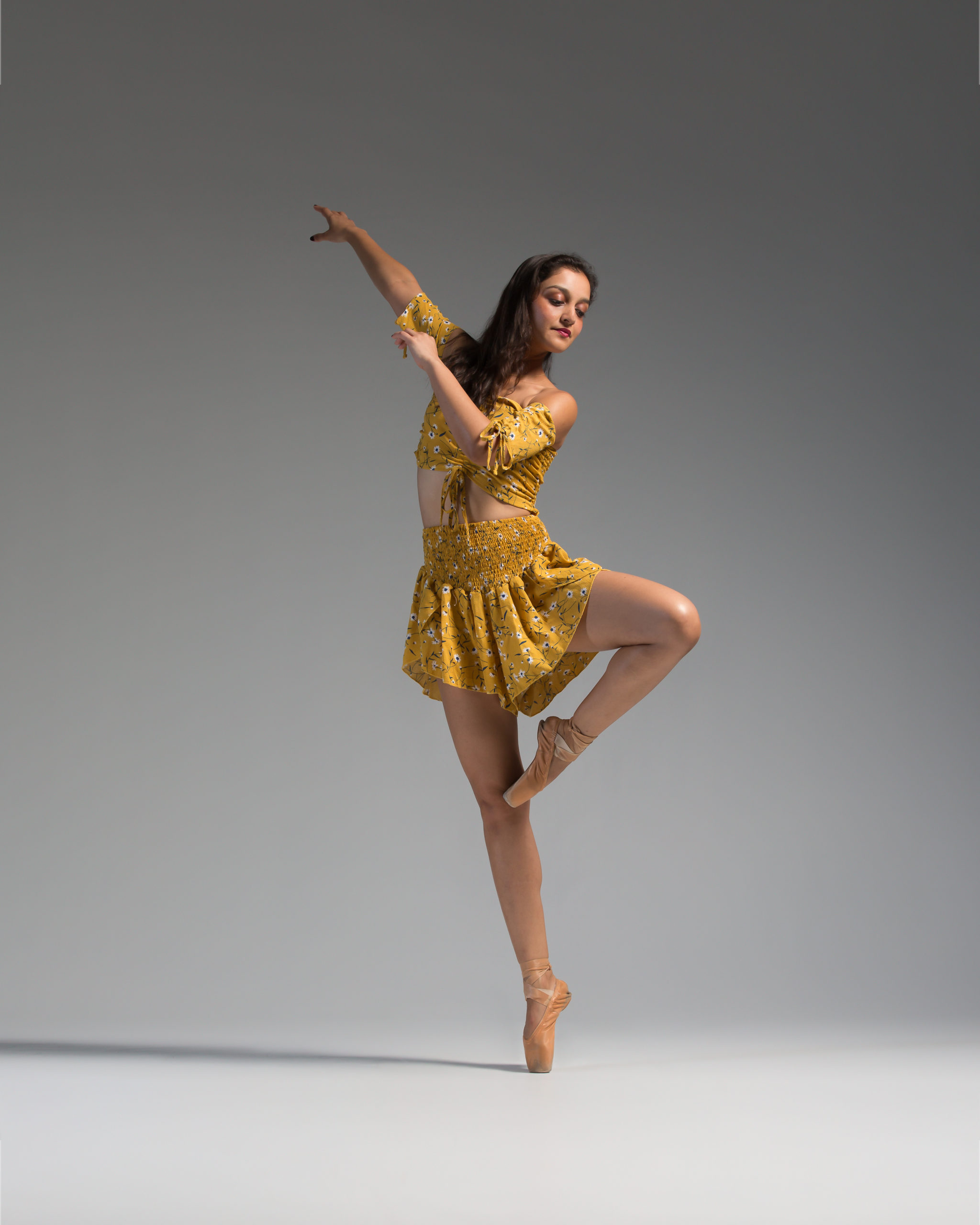 A woman in yellow dress doing a dance move.