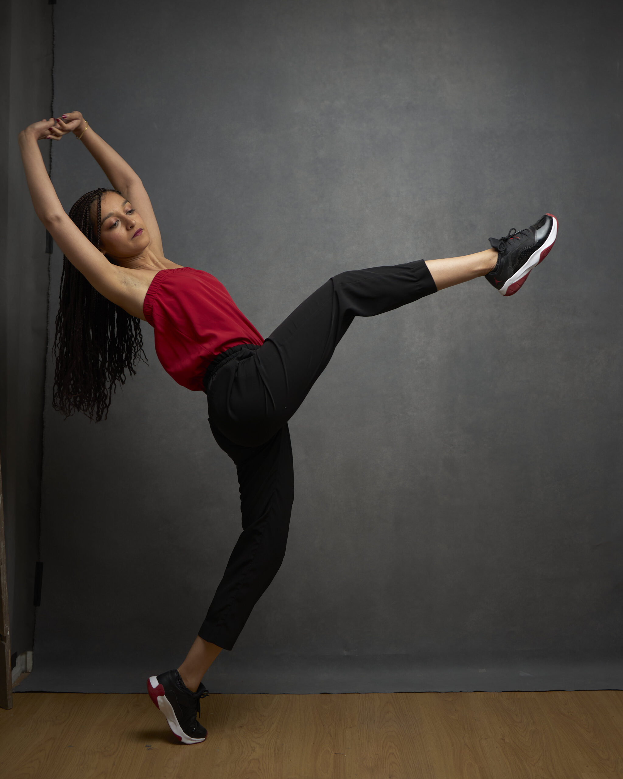 A woman is doing a dance move in front of a wall.