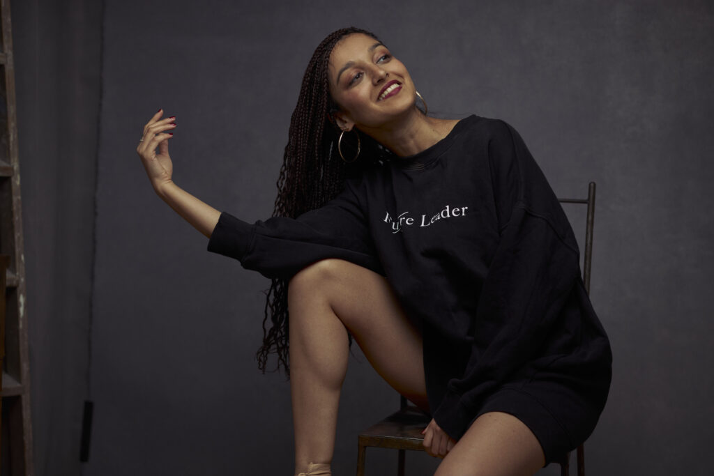 A woman sitting on top of a chair wearing a sweater.