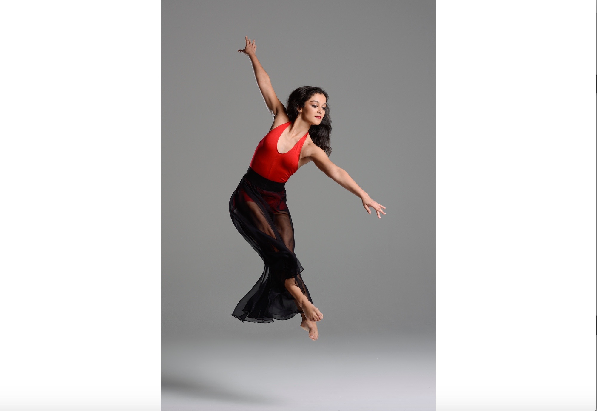 A woman in red and black leotard jumping up.