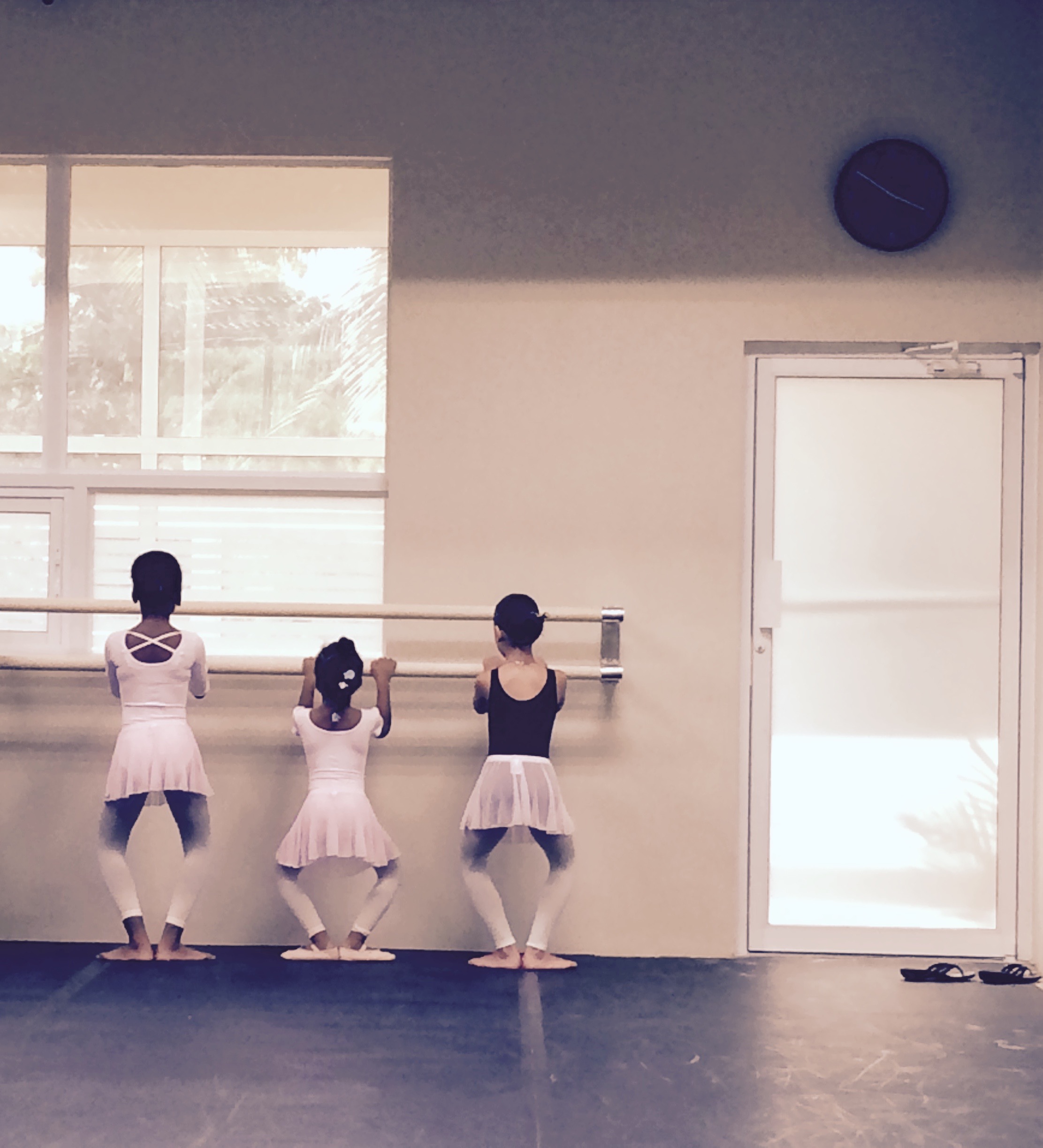 Three young ballerinas are standing in a room.