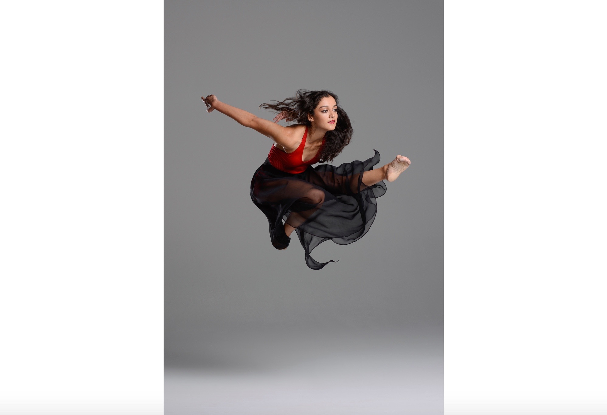 A woman in black dress jumping up into the air.