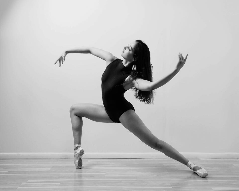 A woman in black leotard and white shoes.