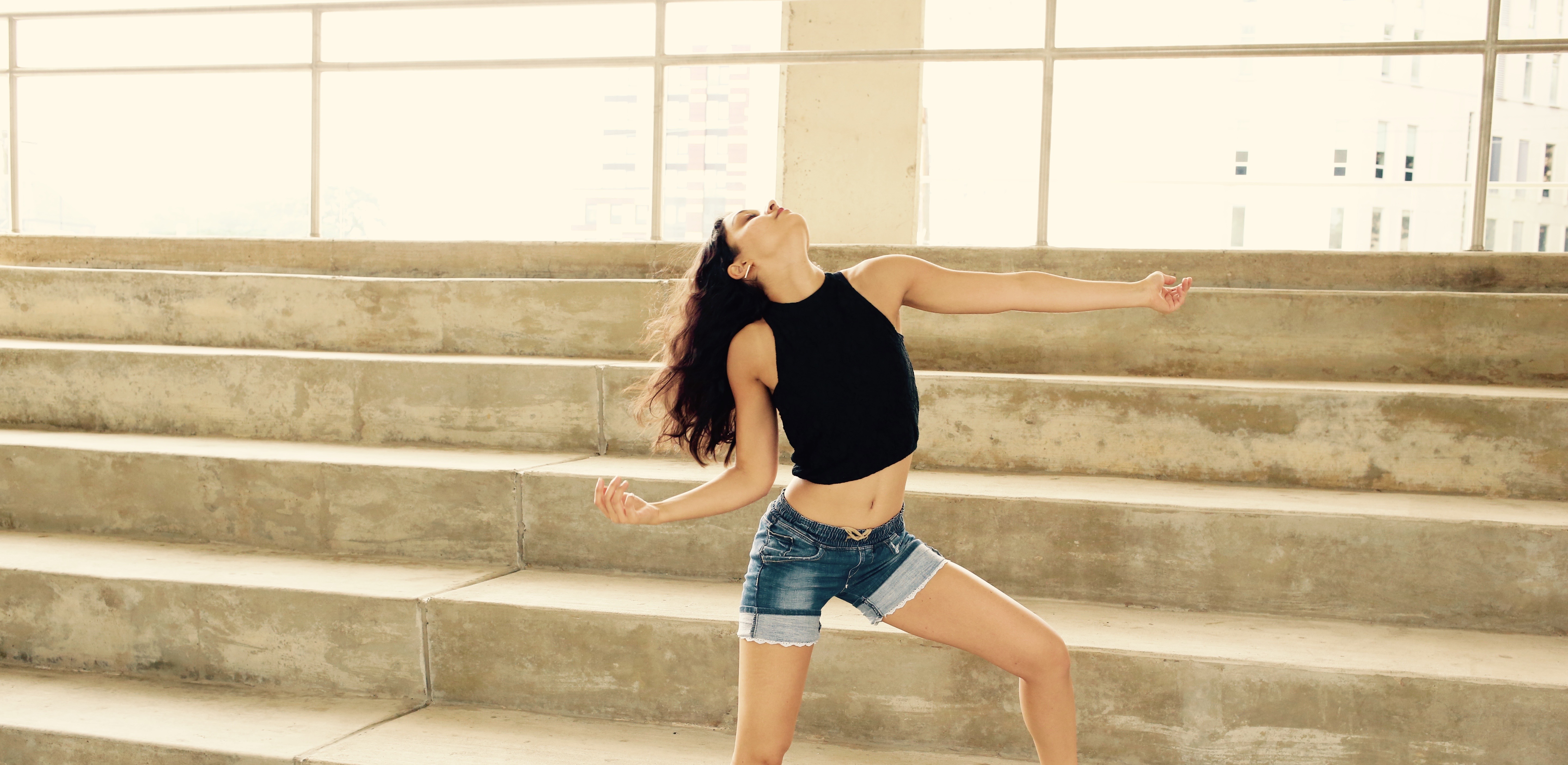 A woman in black shirt and blue shorts jumping.