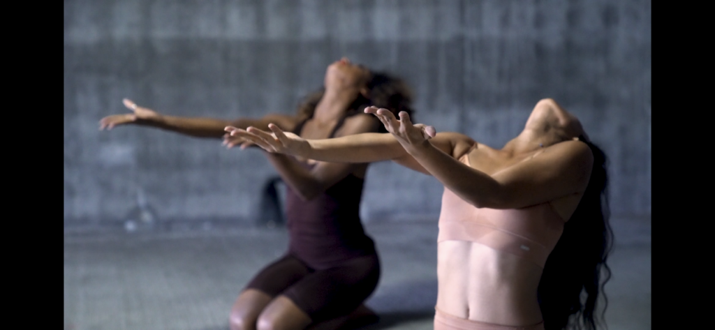 Two people are performing a dance in front of a wall.